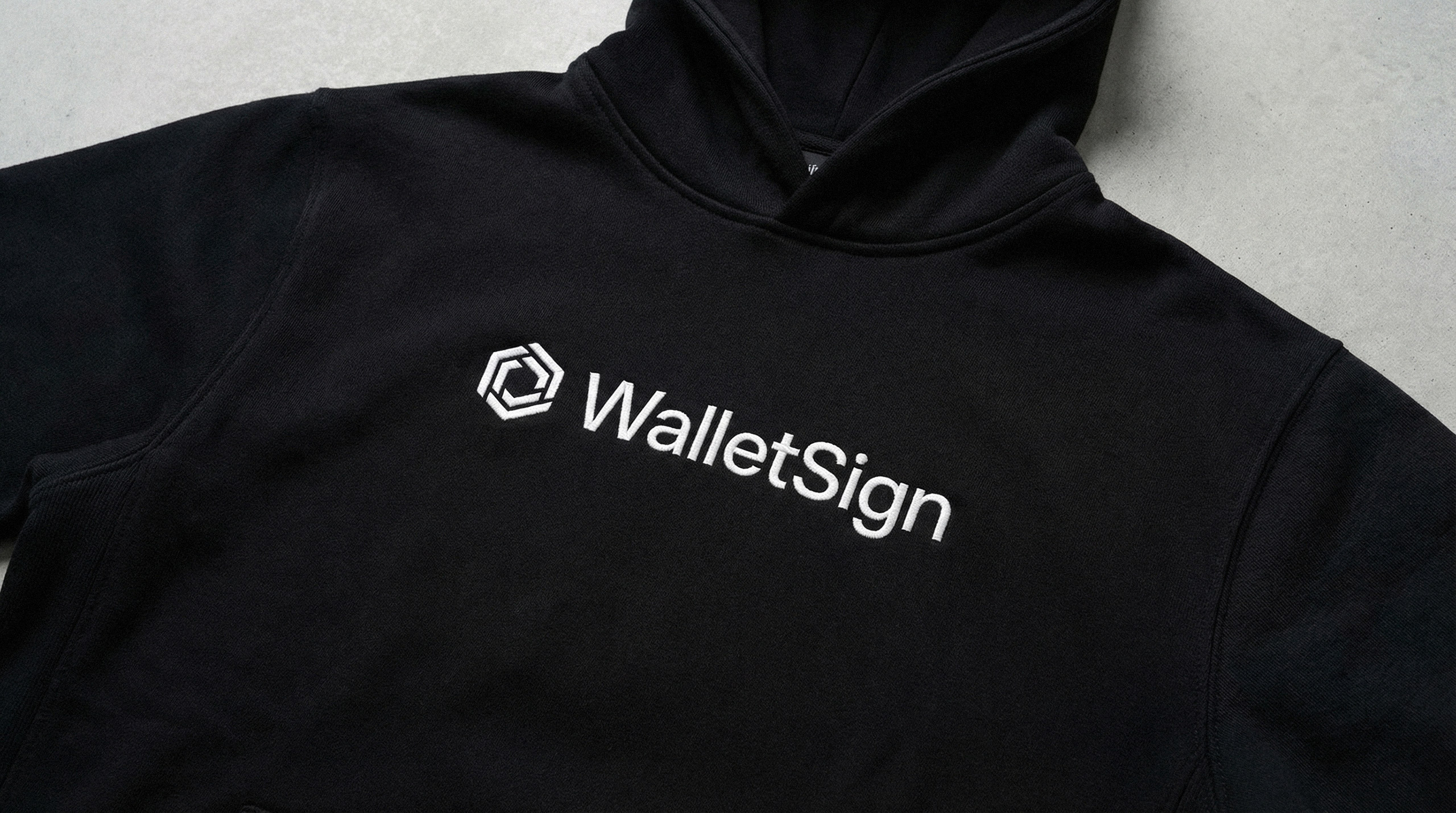 Black streetwear hoodie featuring the WalletSign logo, showcasing the brand's application on physical merchandise for crypto-native teams.