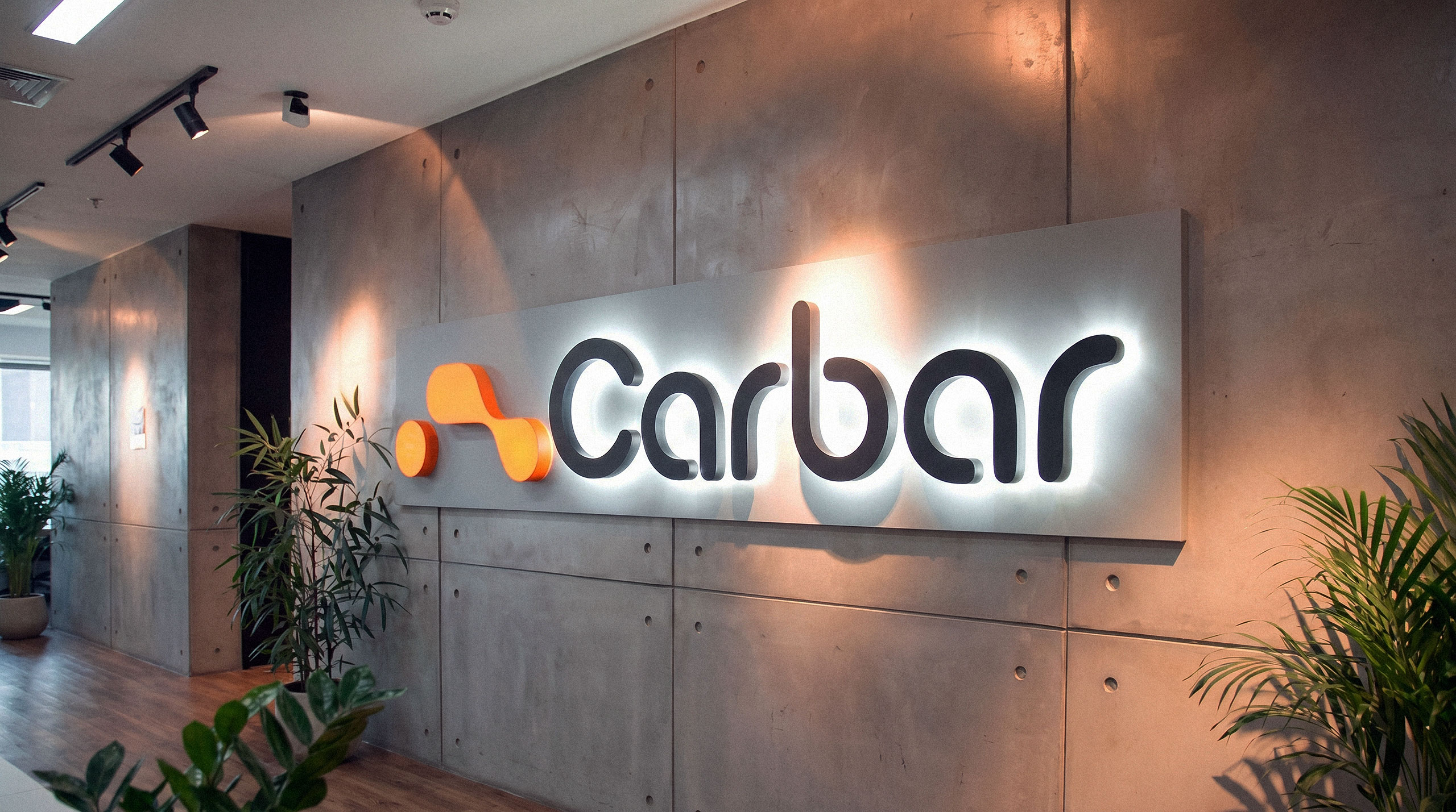 Large backlit 3D Carbar logo mounted on an industrial concrete wall inside a modern office - design by Brandforma Studio.