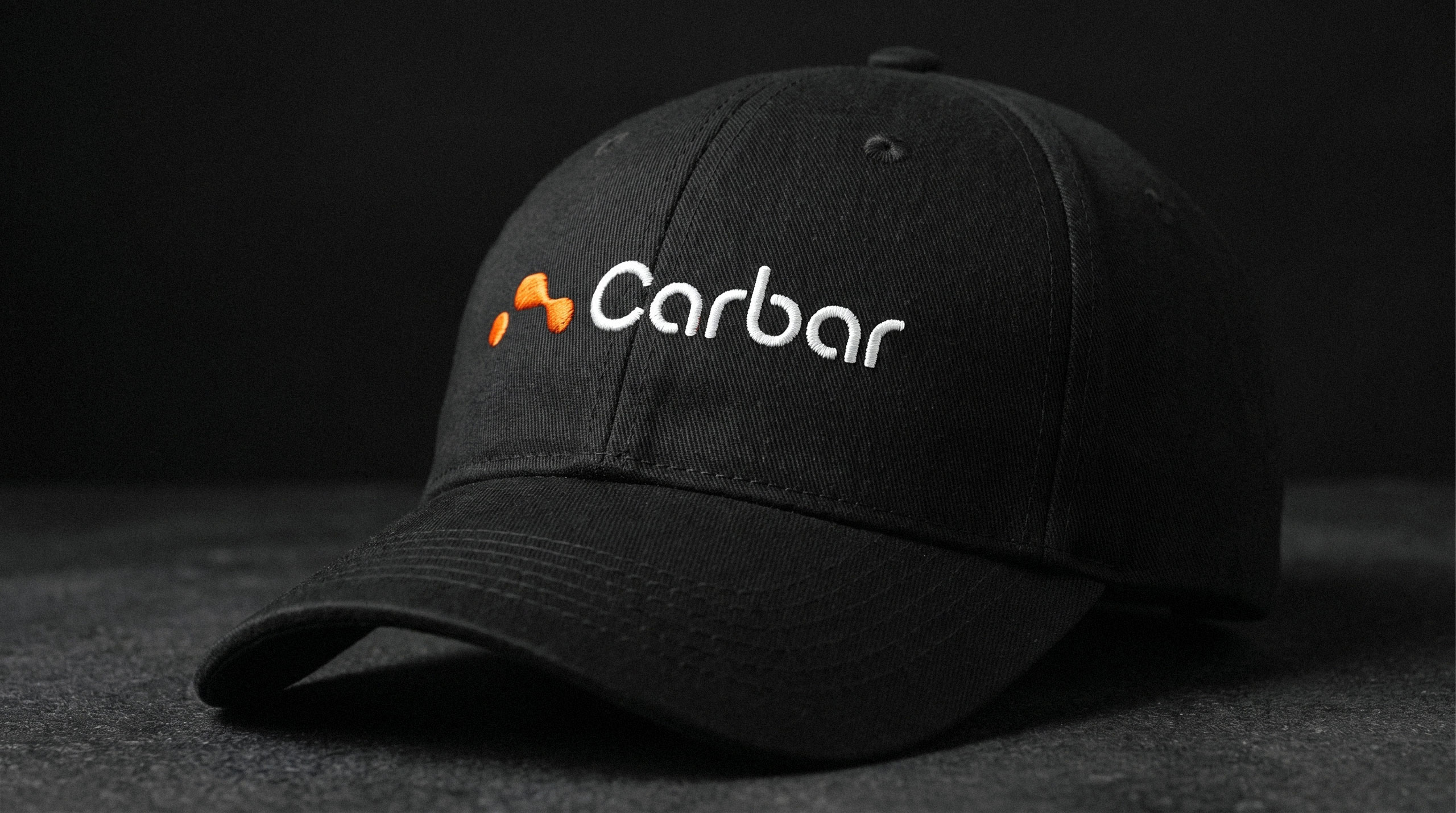 Black baseball cap featuring an embroidered Carbar logo resting on a dark surface - design by Brandforma Studio.