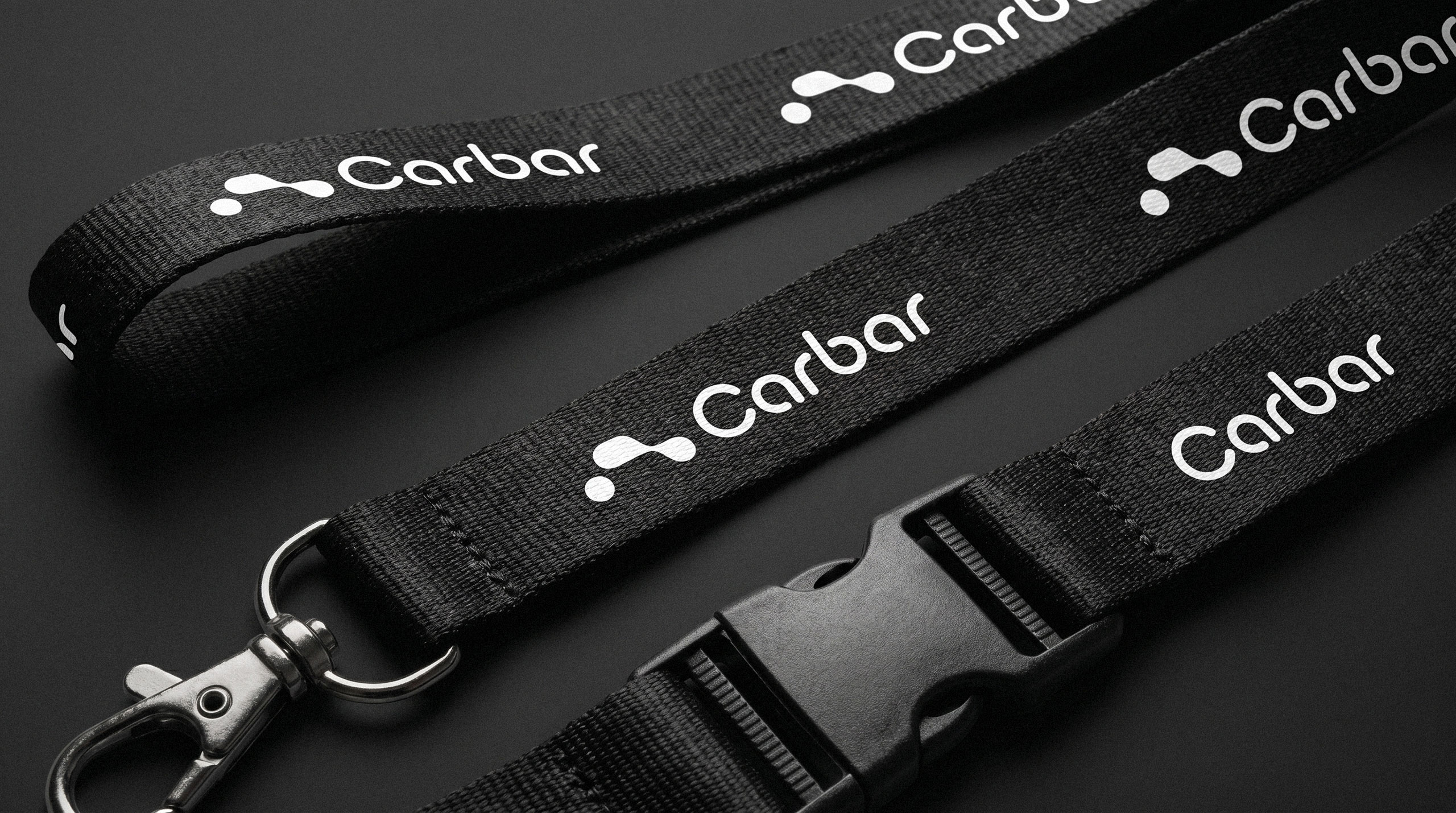 Black corporate lanyards featuring the white Carbar logotype and orange logomark - design by Brandforma Studio.