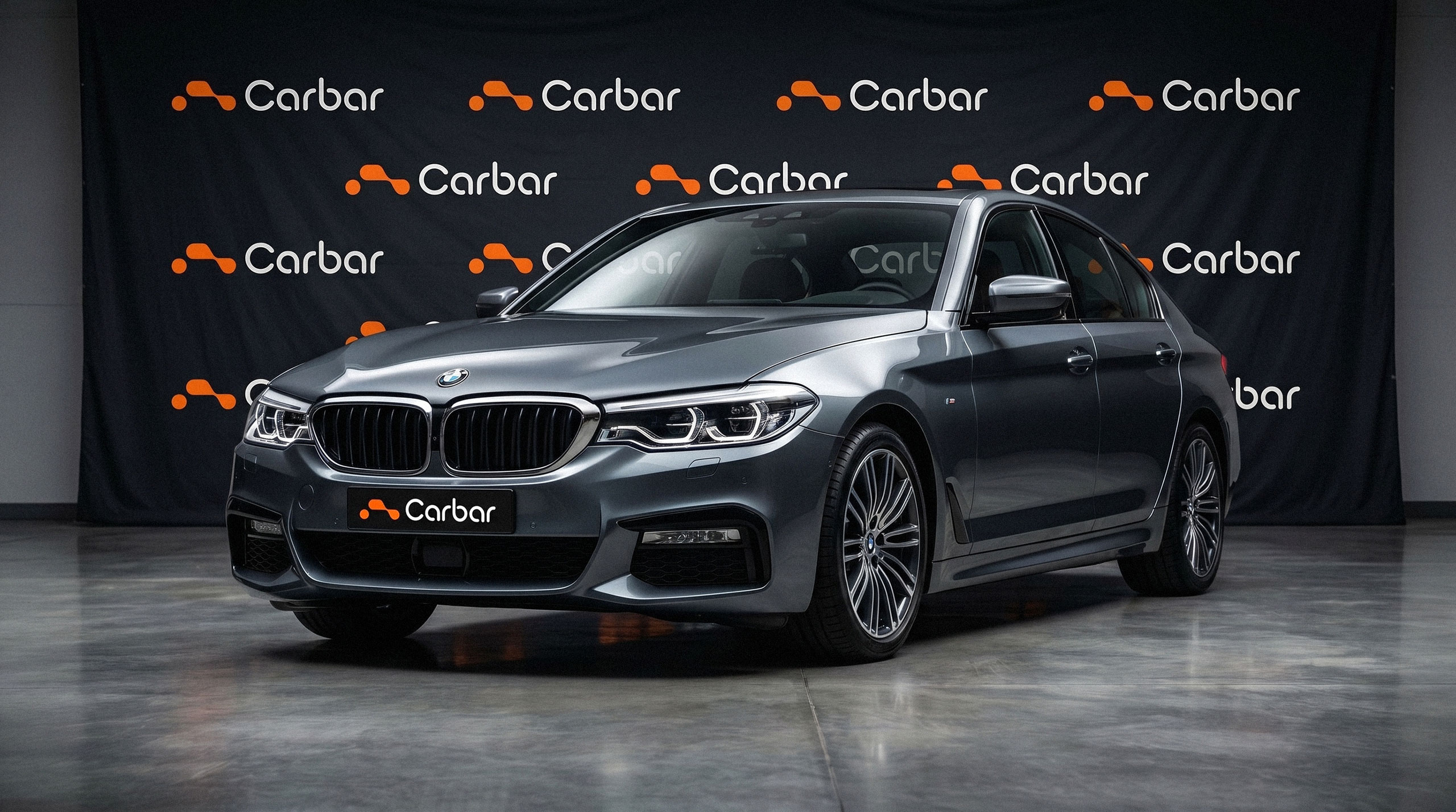 A grey BMW sedan parked in front of a black Carbar branded step-and-repeat backdrop - design by Brandforma Studio.