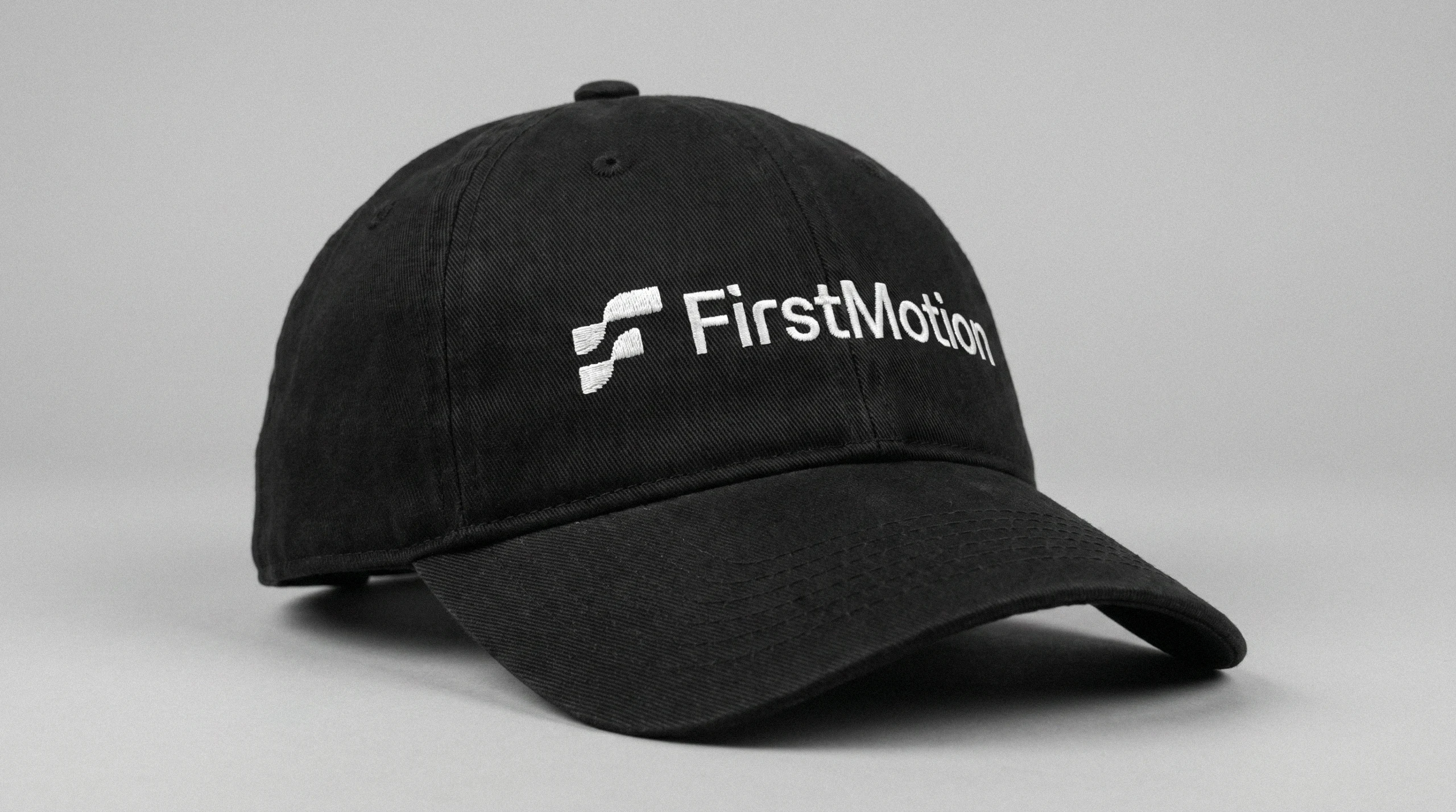 Black FirstMotion baseball cap with embroidered white logo