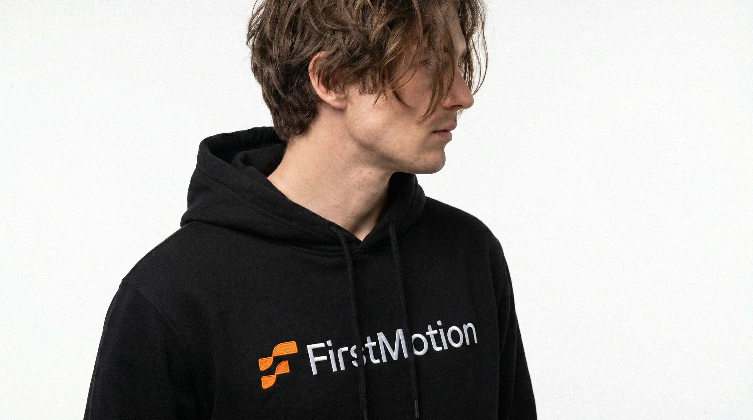 Person wearing a black FirstMotion hoodie with the orange and white logo